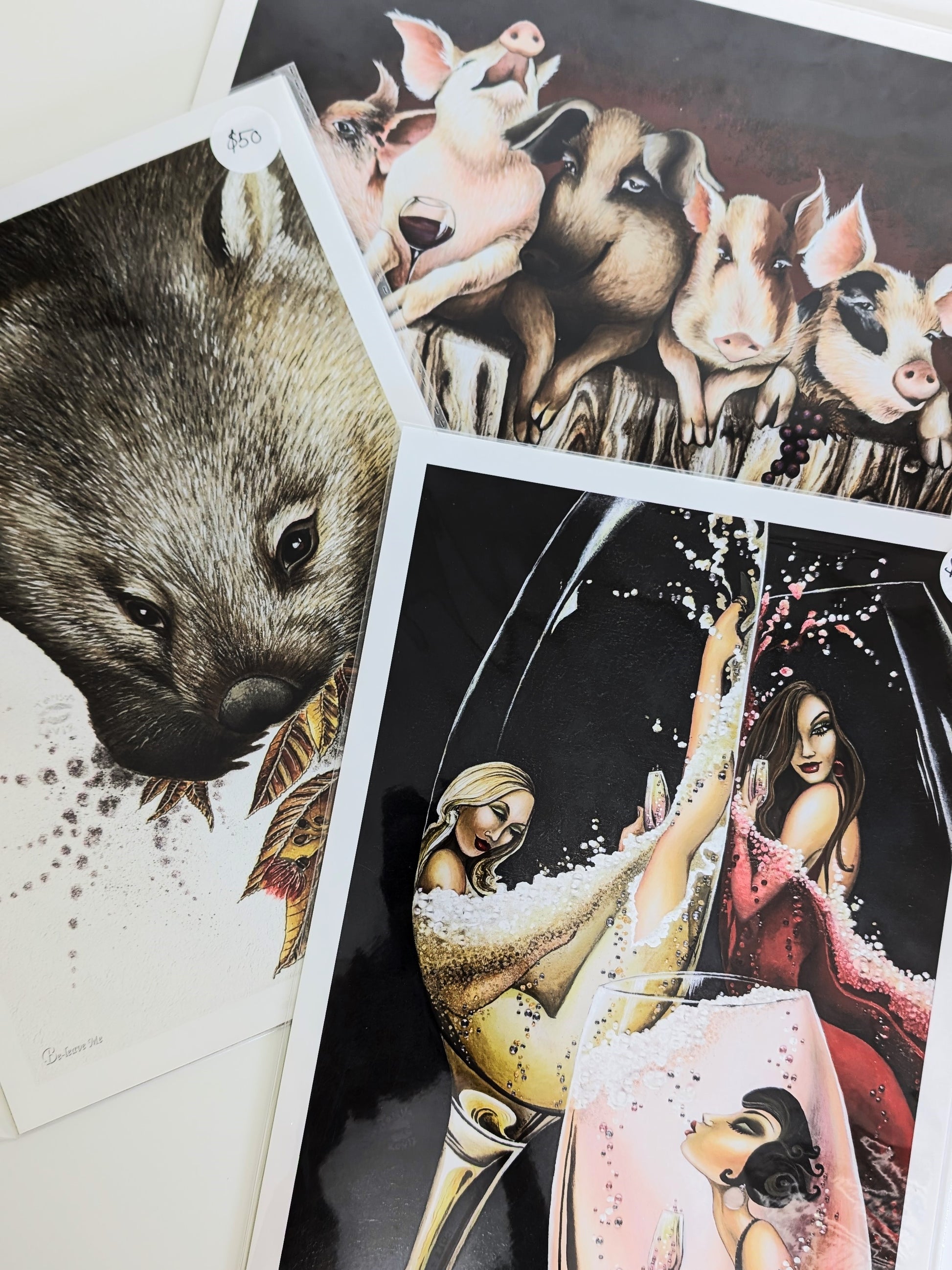 Three artistic prints featuring a wombat, pigs, and a couple with a dog.